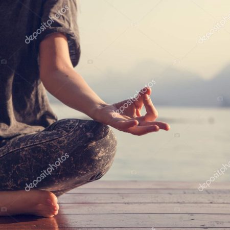 Woman practicing yoga by a lake