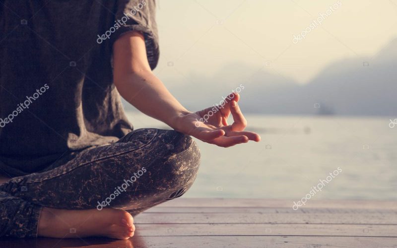 Woman practicing yoga by a lake